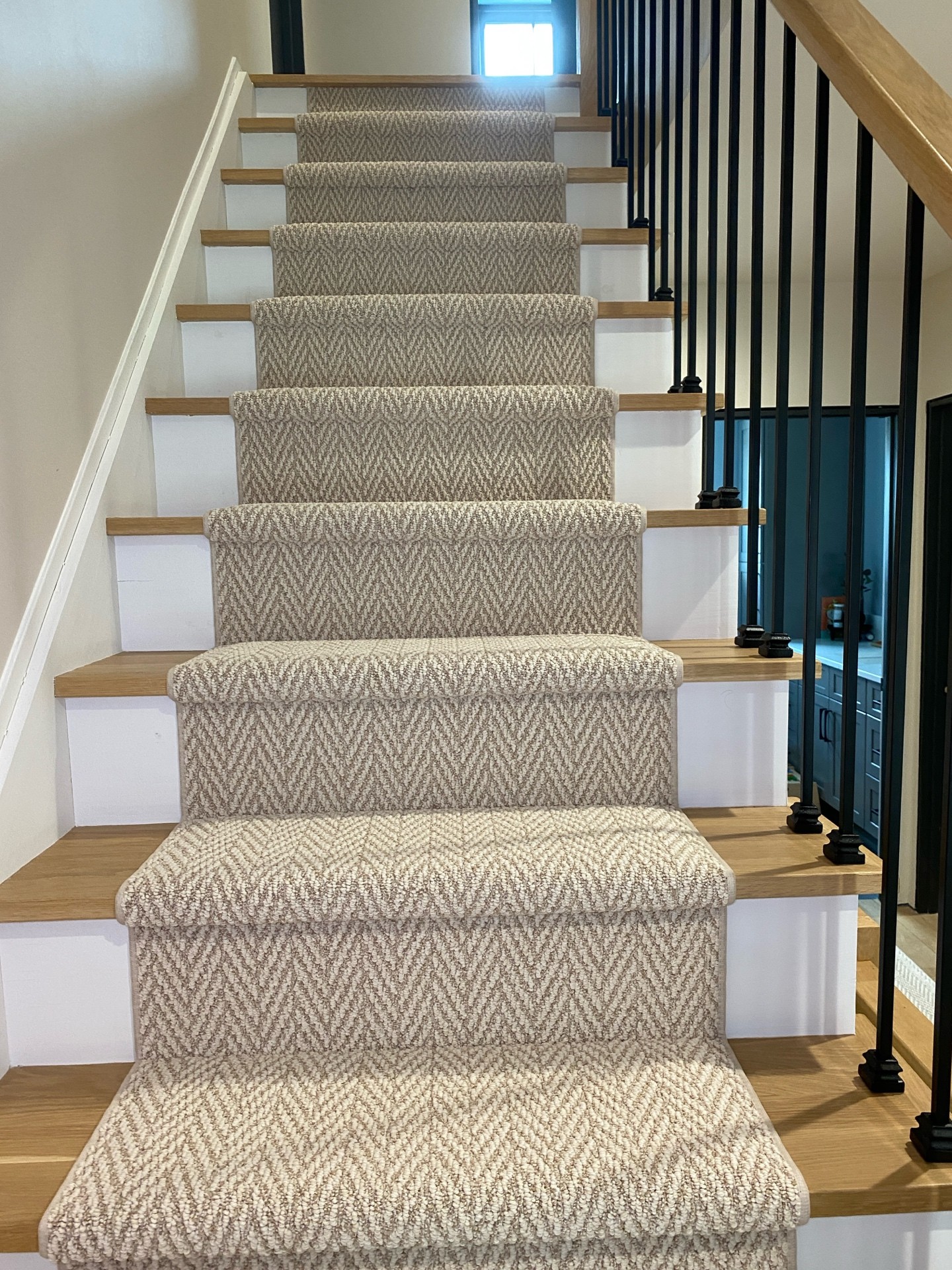 Custom light herringbone stair runner installed on hardwood stairs with exposed wood on both sides