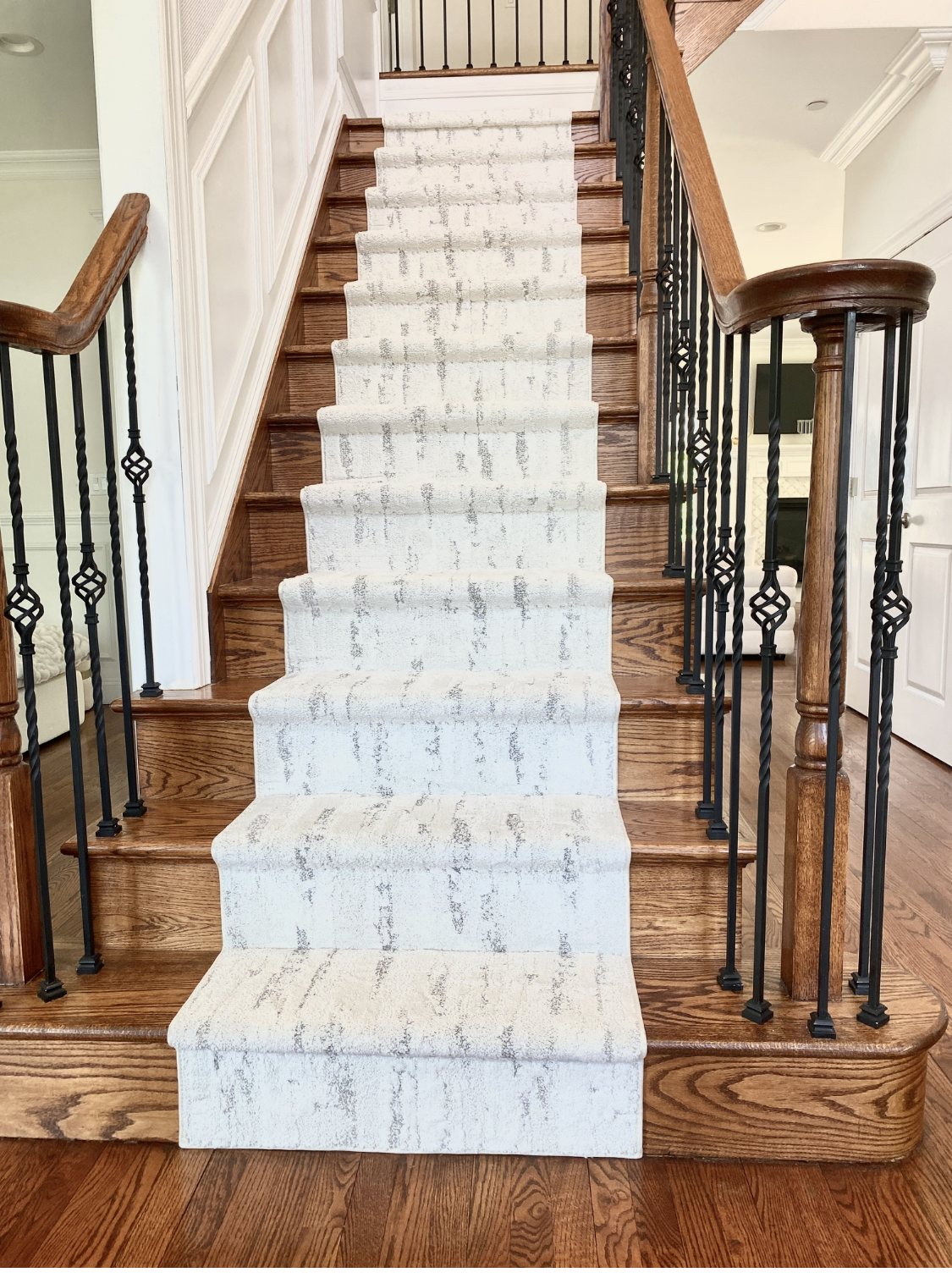 Modern light-colored abstract custom stair runner installed on a traditional wood staircase
