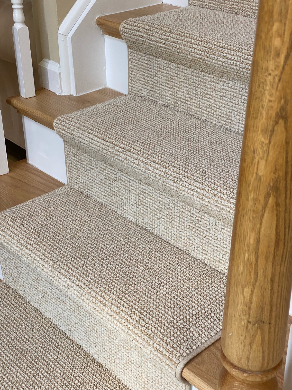 Neutral textured custom stair runner fitted to wood staircase steps