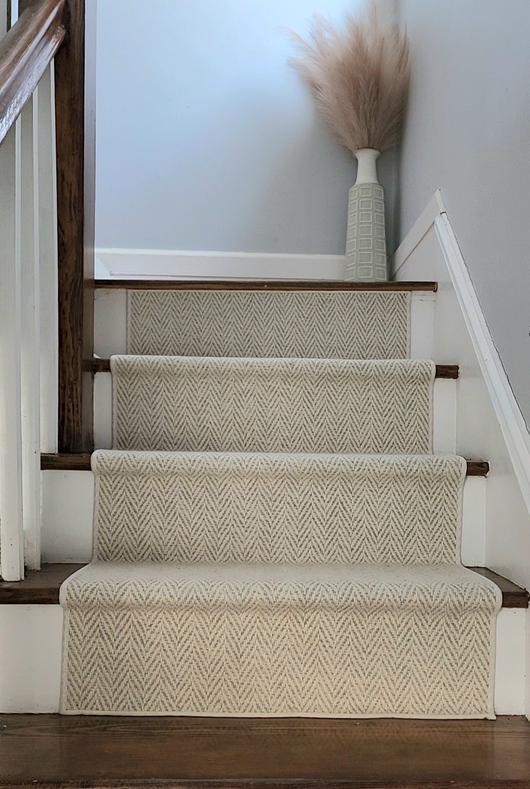 Neutral herringbone stair runner centered on a straight hardwood staircase