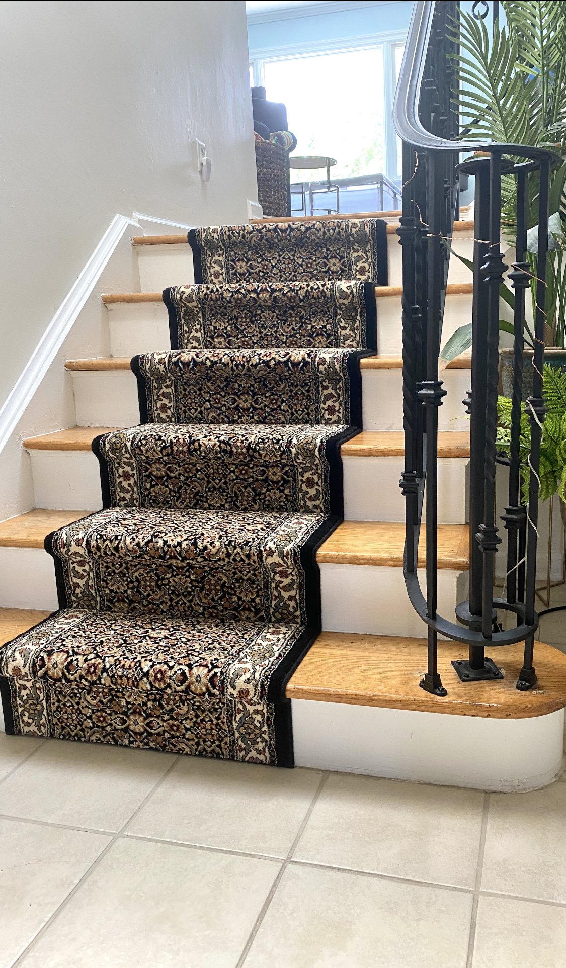 Traditional Oriental-style patterned stair runner with dark border installed on wood stairs